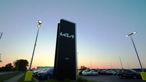 Illuminated sign post of Kia car dealership on twilight blue sky background Stock Footage 317732897