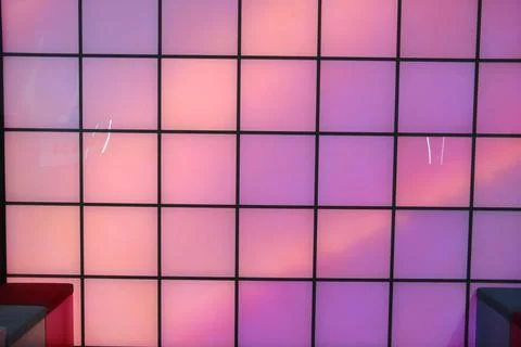 Illuminated square panels in a grid pattern display vibrant pink and purple Stock Photos