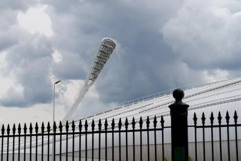 Illuminated stadium tower under dramatic clouds during evening hours Stock Photos