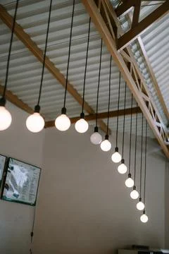 Illuminated string of decorative lightbulbs hanging from wooden roof structur 写真素材