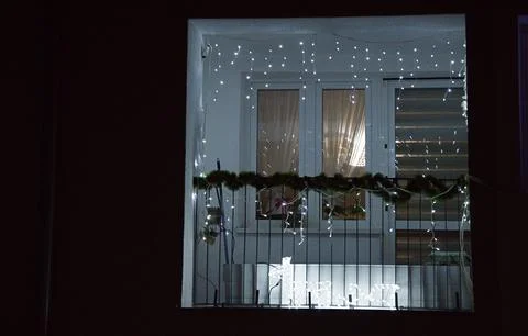 Illuminated string lights and garlands on a decorated balcony at night in a.. Stock Photos