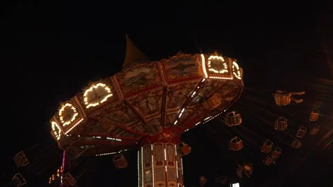 Illuminated Swing Carousel in Motion Against a Black Night Sky at an Amusement Stock Footage 296589403
