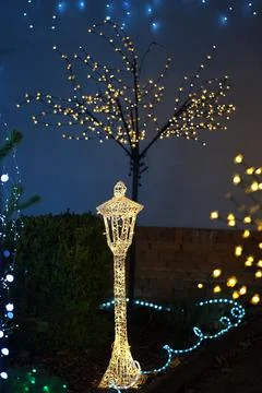 Illuminated tree lit up with blue and yellow string lights and a decorative.. Stock Photos