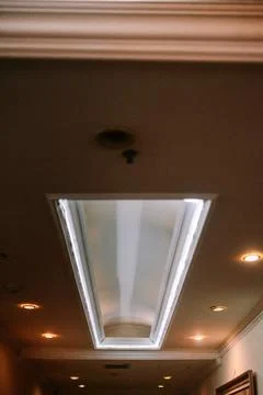 Illuminated triangular ceiling detail and recessed lighting arrangement Stockfoto's