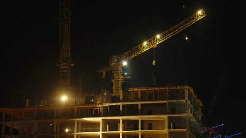 Illuminated yellow construction crane working on building site at night. Stock Footage 342372599