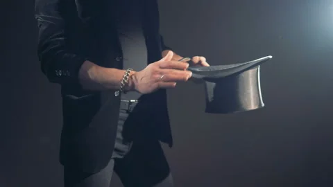 Illusionist is making slow passes over his hat and making impression of taking Stock Footage 86149582