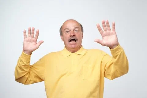 I'm afraid. Portrait of senior scared man in yellow pulover. . Male half-length Foto stock