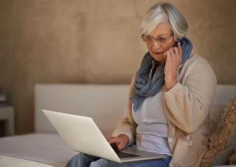 Im checking my emails now.... A senior woman on her mobile while using her la 스톡 사진