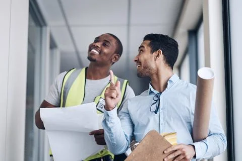 Im trusting you to fix this. two young architects standing together and having a Stock Photos