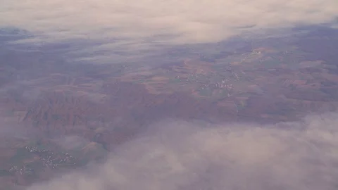 Image above the clouds of small villages and farmlands during the day. Video stock 127217477