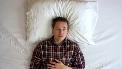 Image from above of man having uncontrollable laughing at bed. Video stock 132184445