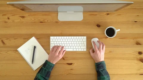Image from above of man typing at keyboard, working from home, during the day. Video stock 128772702