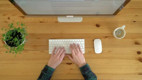 Image from above of man typing at keyboard, working from home, during the day. Stock Footage 128774886