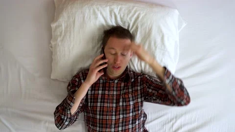 Image from above of young man talking at the cellphone while lay down. Video stock 132184428