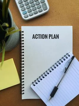 Image with action plan text on a note pad with pen, plant, calculator and sticky Foto stock