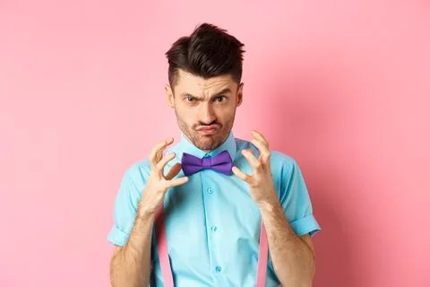 Image of angry guy in bow-tie gonna strangle someone, raising hands up and Stock Photos