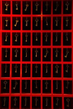 Image of an array of assorted golden keys in vibrant red frames 写真素材