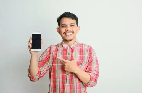Image of asian man holding phone, isolated on grey background. advertising .. Stock Photos