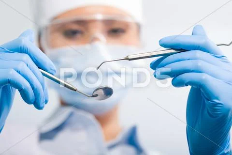 Image of assistant in sterile mask holding dentistry tools in hands Stock Photos