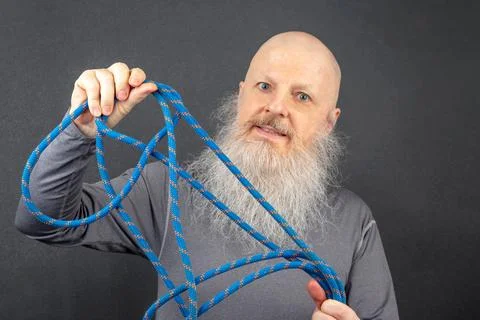 Image of a Bald, Bearded Man Grasping a Bright Blue Climbing Rope, Set Agai.. Stock Photos