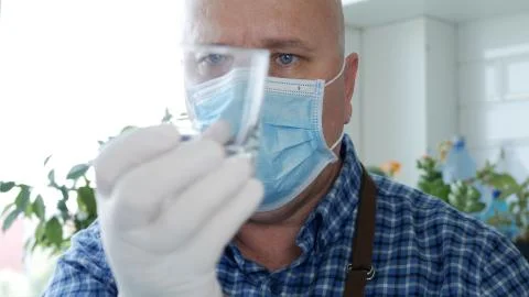 Image with a Bartender Wearing Protective Gloves and Face Mask Cleaning a Gla 스톡 사진