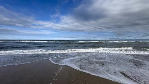 Image of a beach with a horizon separating the sea from the sky. Waves break Stock Photos