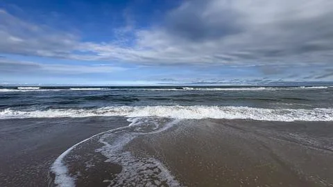 Image of a beach with a horizon separating the sea from the sky. Waves break Foto stock