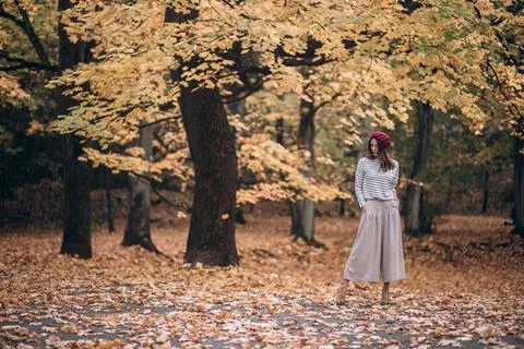 Image of a beautiful brunette woman in a red beret walks in the park in autumn Stock Photos