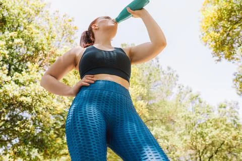 Image from below of a young athlete drinking water to refresh herself from a Stock Photos