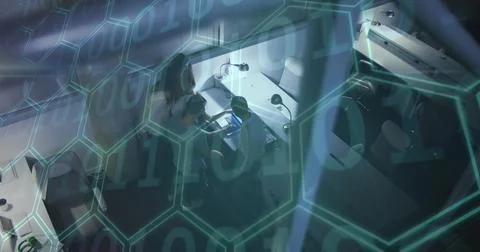Image of binary coding and hexagons over team of people using laptop Foto stock
