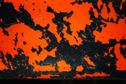 The image is of a black and orange surface with a lot of paint and scratches Foto stock