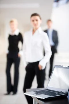 Image of black computer lying on the table on the background of three people Stock Photos