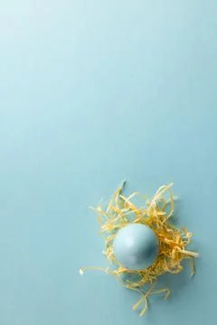 Image of blue easter egg in straw and copy space on blue background Stockfoto's