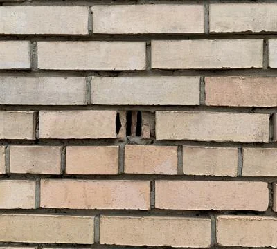 Image of a brick wall of a building with damaged bricks. Stock Photos