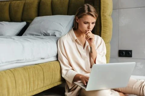 Image of brooding woman working with laptop while sitting on floor Stock Photos