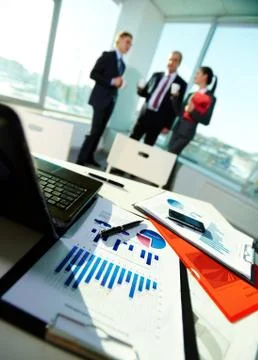 Image of business documents on workplace with three partners on background Stock Photos