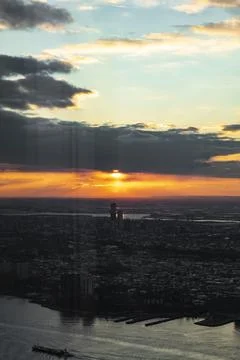 The image captures a cityscape during sunset, with the sun peeking through th Stock Photos