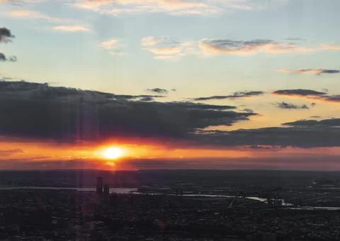 The image captures a cityscape during sunset, with the sun peeking through th Foto stock
