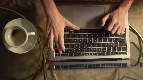 This image captures a closeup view of hands actively typing on a laptop while a Stock-Footage 289964362