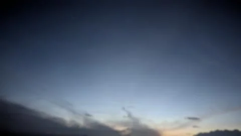 The image captures a deep blue twilight sky. Wispy clouds linger near the d.. Stock Photos