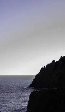 The image captures a dramatic contrast between the dark silhouette of a rocky Stock Photos