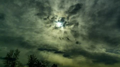 This image captures a dramatic sky with sun rays breaking through thick, da.. Stock Photos