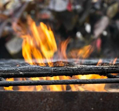 The image captures a dynamic scene of orange flames rising through the grates Stock Photos