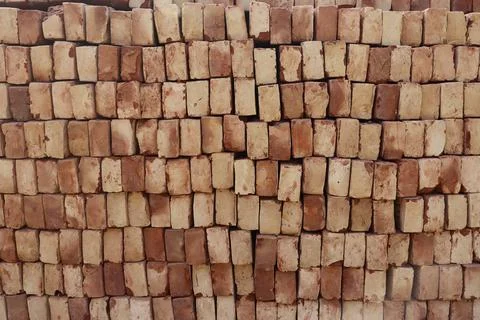 Image captures a large stack of pale red bricks, each with a unique texture,  Stock Photos