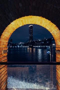 The image captures a nighttime view of a cityscape through a brick archway,.. Stock Photos