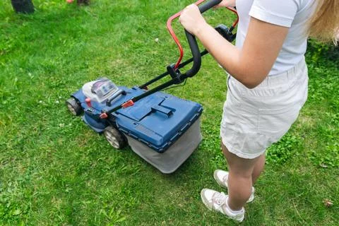 This image captures someone mowing their lawn with a push lawn mower. The p.. Stock Photos