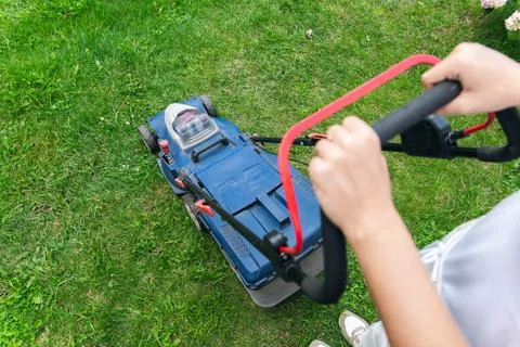 This image captures someone mowing their lawn with a push lawn mower. The p.. Stock Photos