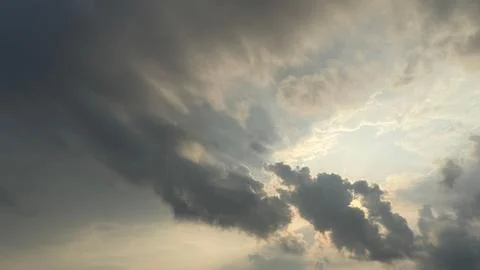 The image captures sunlight breaking through thick cumulus clouds, creating a Photos