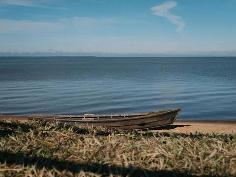 This image captures a tranquil coastal scene with an old wooden boat lying on Stock-Fotos