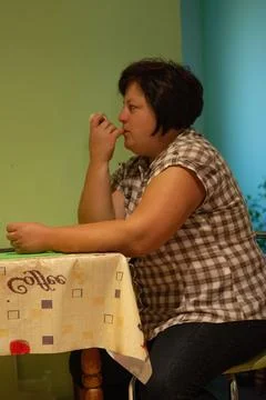 This image captures a woman at a kitchen table, featuring a contemplative pos Stock Photos